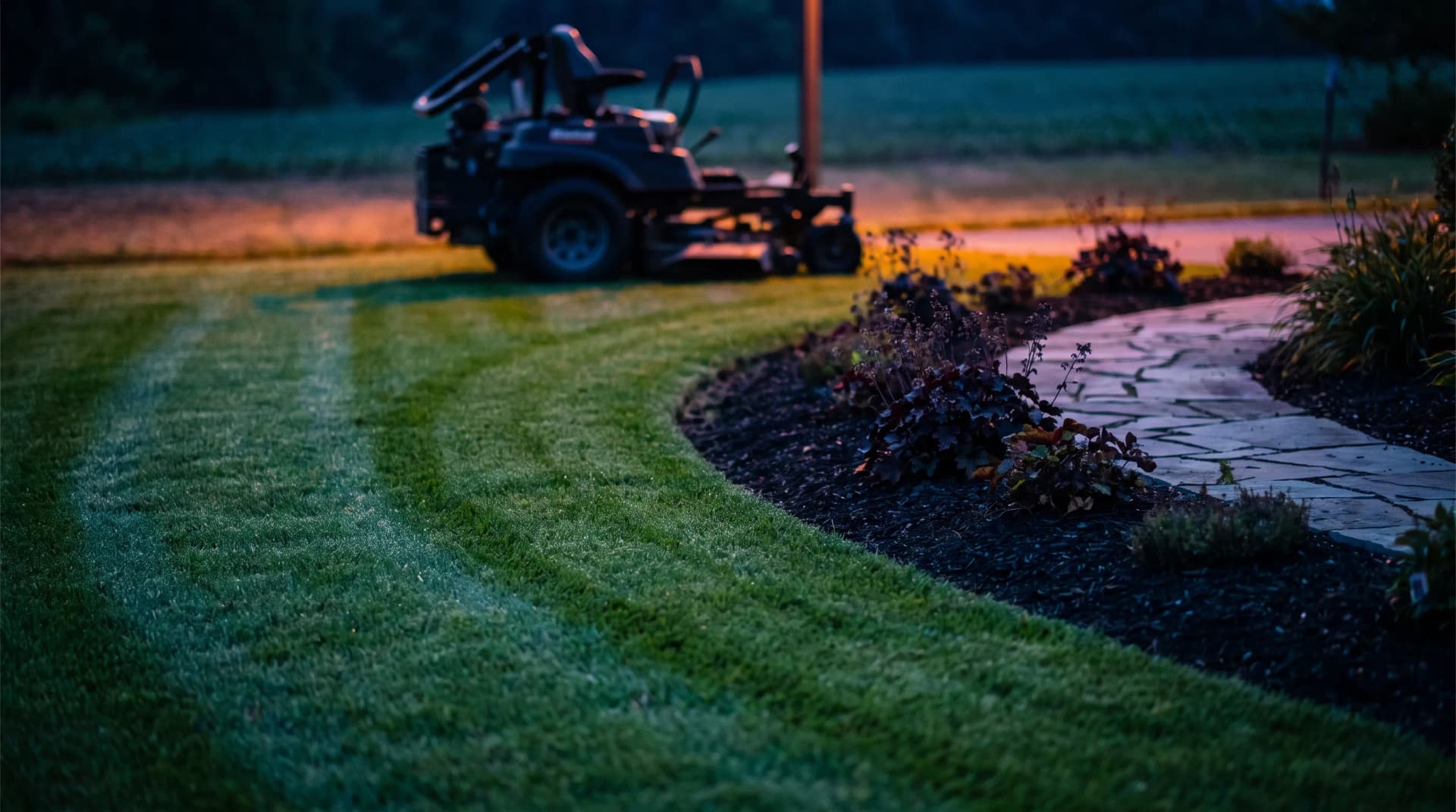 Manicured green lawn with mowing stripes, stone path and flower beds, landscapers & lawn care marketing